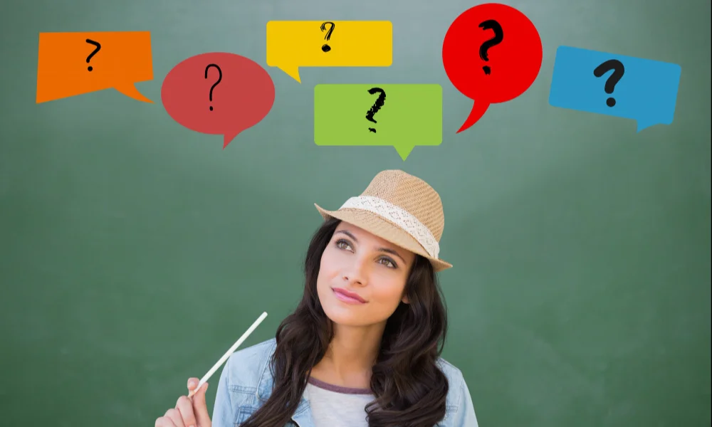 A thoughtful woman wearing a hat holds a pen