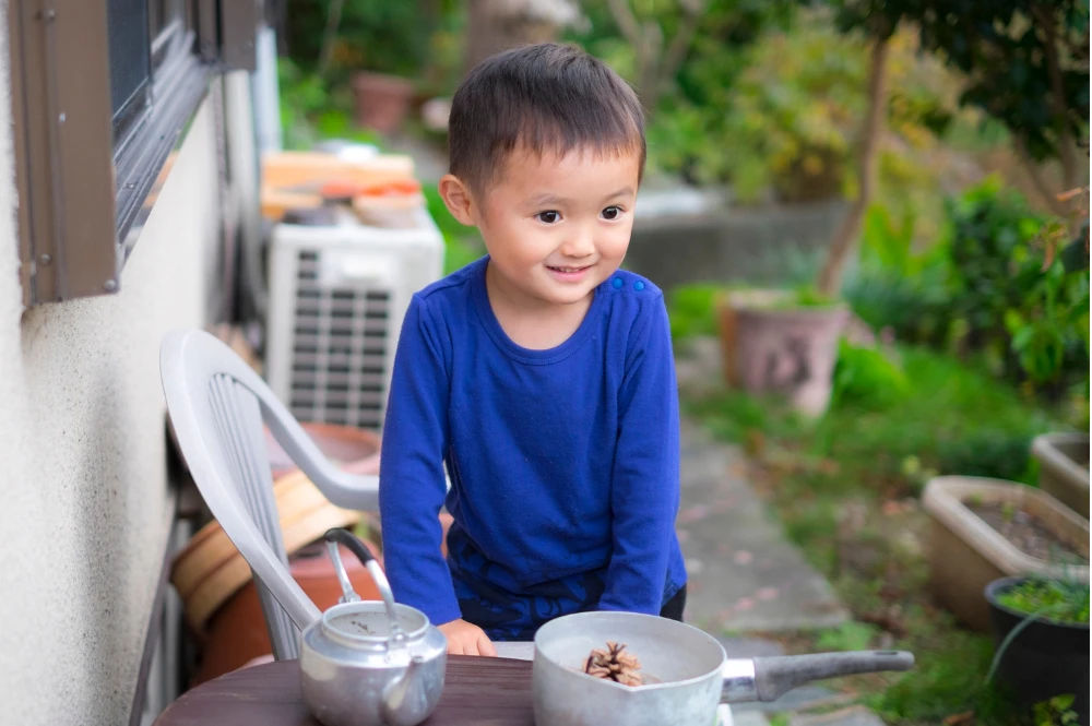 A young boy sits on a chair, smiling and enjoying his time in a cozy setting.