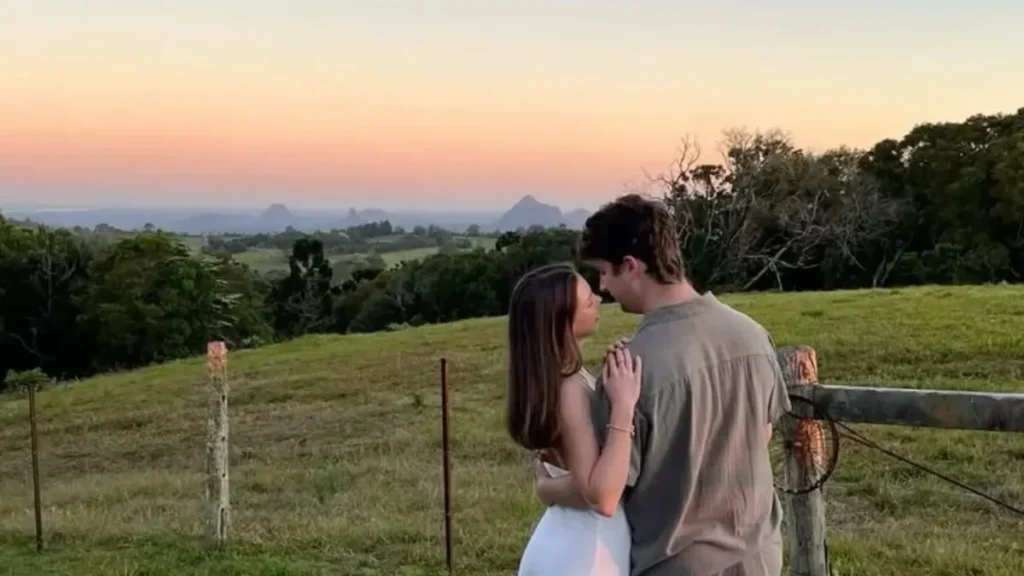 couples trivia questions featured in a photo of a romantic young couple embracing in a grassy field during a scenic sunset.