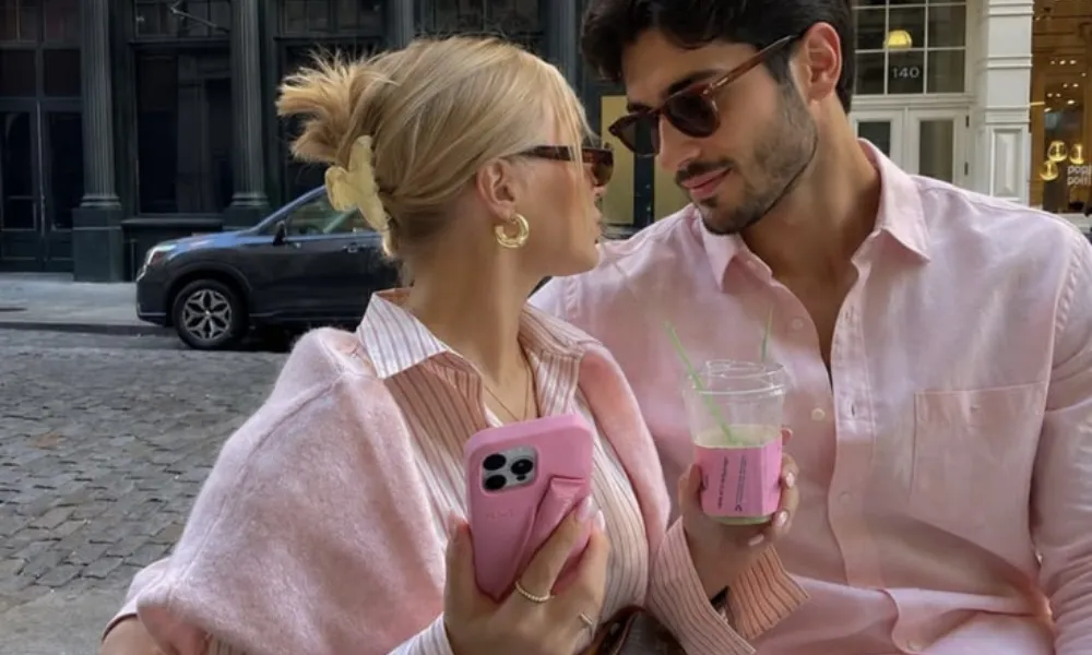 couples trivia questions featured in a photo of a stylish couple in color-coordinated pink shirts enjoying drinks together outdoors in the city.