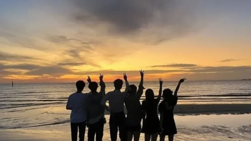 Friends silhouette making peace hand signs during beach sunset for creative Names for Group Chats.