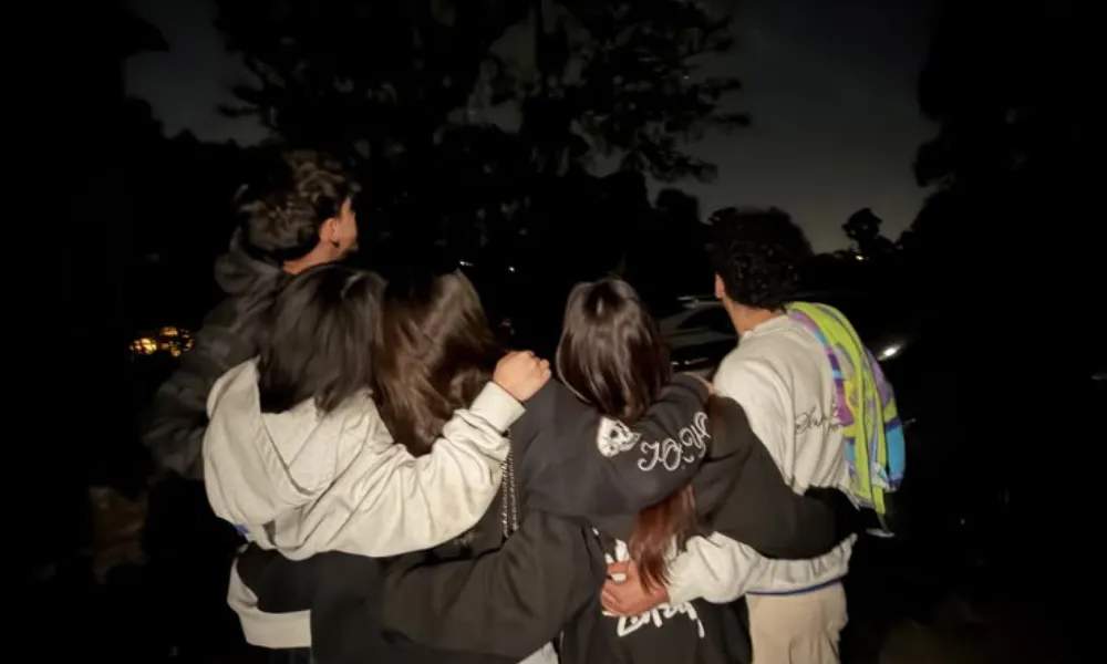 Close friends embracing during a night gathering for Funny Names for Group Chats.
