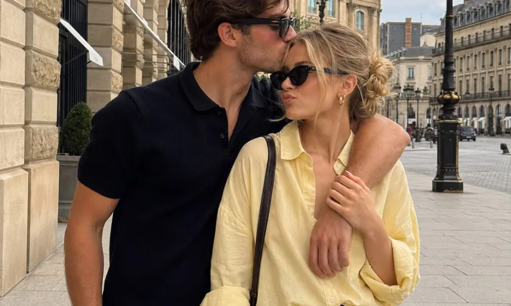 couples trivia questions featured in a photo of a stylish man kissing a woman on the forehead while standing on a European city street.
